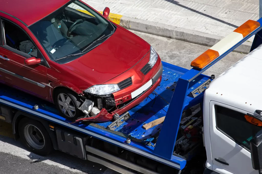 A crashed car ready to be towed by a truck.