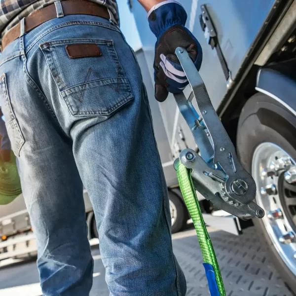 A zoomed image of the driver of the tow truck with strap cable in his hands.